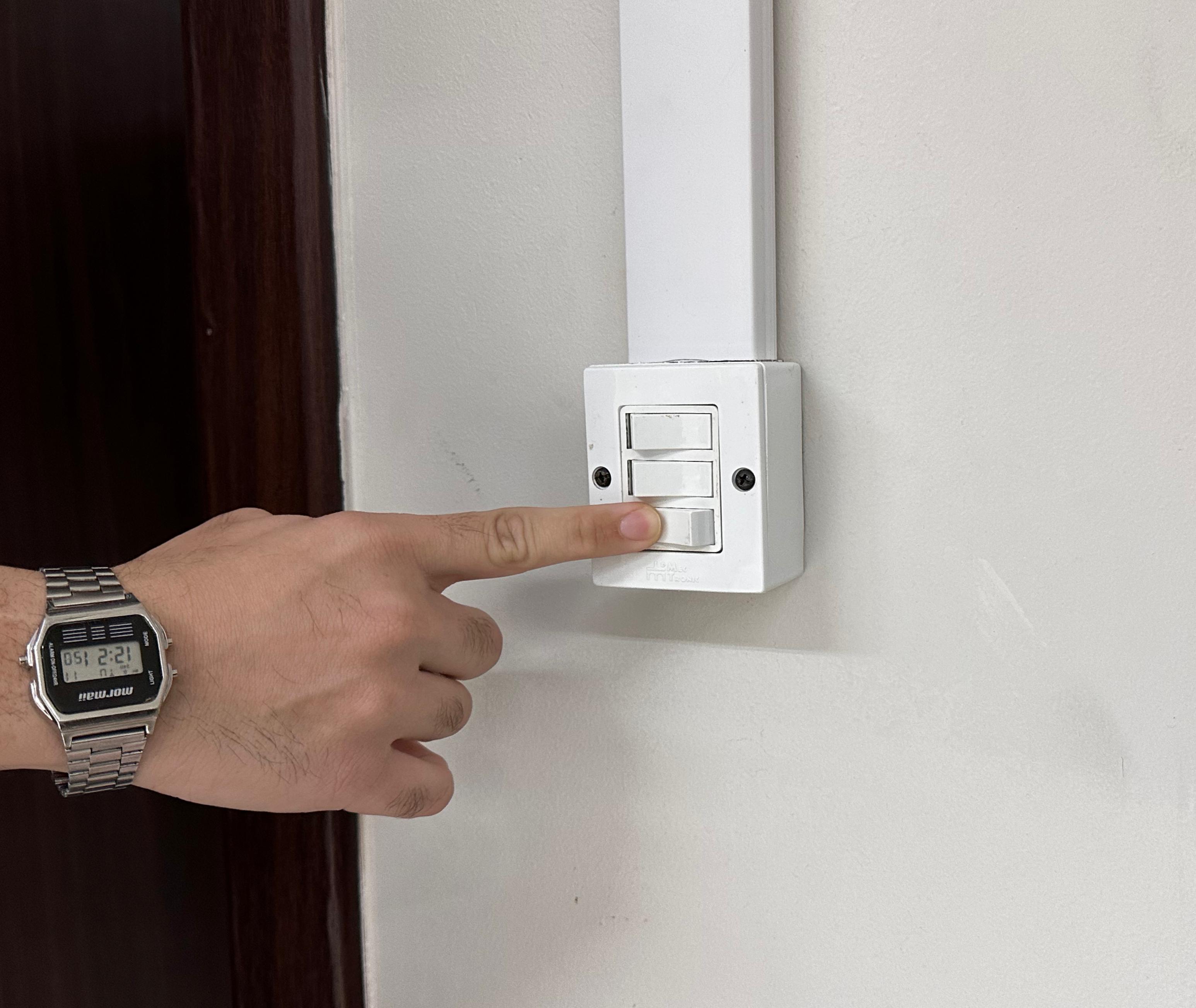 foto colorida com enfoque nas mãos apagando a luz no interrupitor