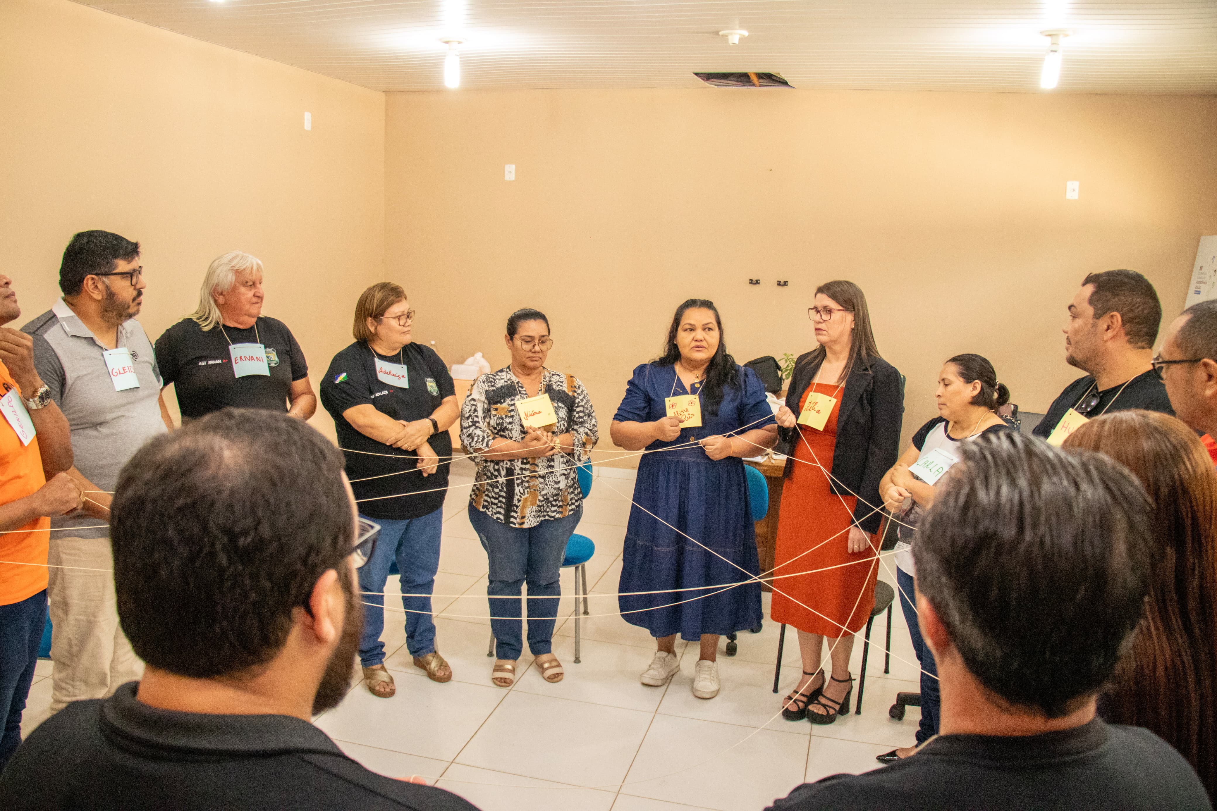 foto colorida de um grupo de pessoa em círculos segurando barbantes  