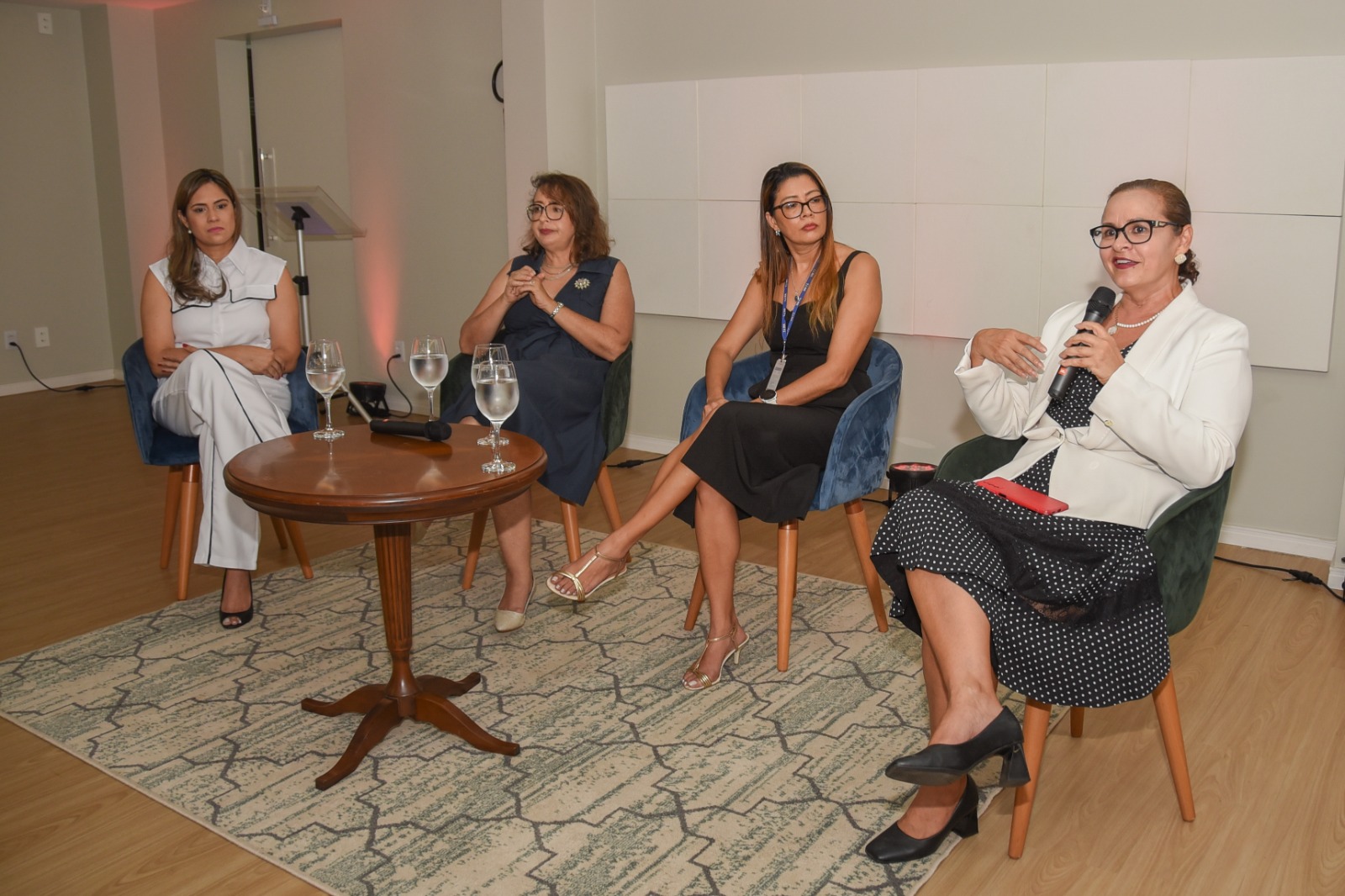 Foto colorida mostra quatros mulheres sentadas durante a palestra