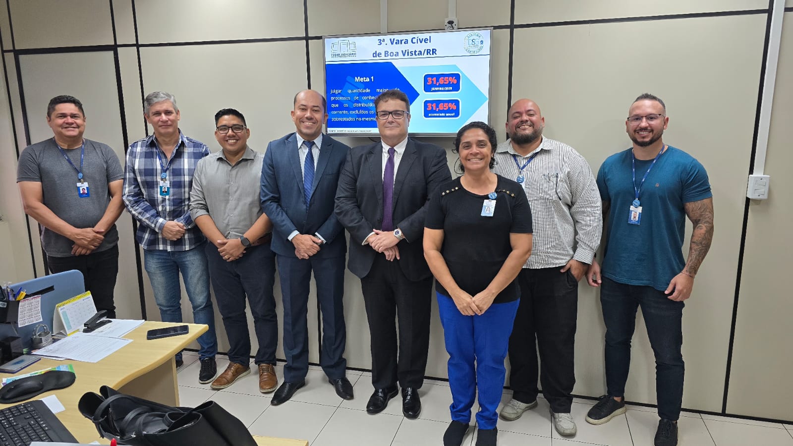 Imagem colorida contem o juiz Coordenador dos Núcleos de Justiça 4.0, Rodrigo Bezerra Delgado, posando para fotografia ao lado de mais sete pessoas, sendo cinco servidores do TJRR, durante ação de auditoria interna, para segunda fase de certificação do ISO 9001:2015. Logo atrás deles, encontra-se um aparelho televisivo e na tela se encontra o texto “3ª Vara Cível de Boa Vista/RR”. Imagem colorida contem o juiz Coordenador dos Núcleos de Justiça 4.0, Rodrigo Bezerra Delgado, posando para fotografia ao lado de mais sete pessoas, sendo cinco servidores do TJRR, durante ação de auditoria interna, para segunda fase de certificação do ISO 9001:2015. Logo atrás deles, encontra-se um aparelho televisivo e na tela se encontra o texto “3ª Vara Cível de Boa Vista/RR”.