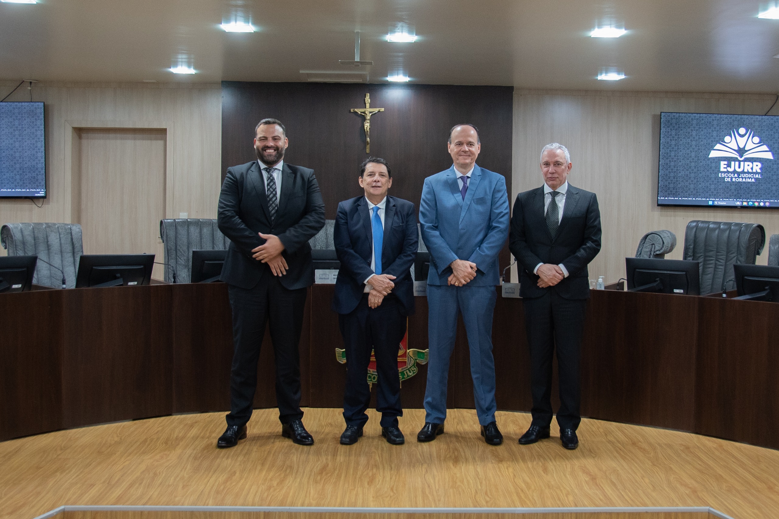 Foto colorida mostra quatro homens em pé posando para a foto em frente ao TRibunal pleno do TJRR. Da esquerda para a direita:o juiz auxiliar da Presidência do CNJ, Dorotheo Barbosa Neto, o desembargador Jésus Nascimento,o desembargador Cristóvão Suter e o desembargador Almiro Padilha