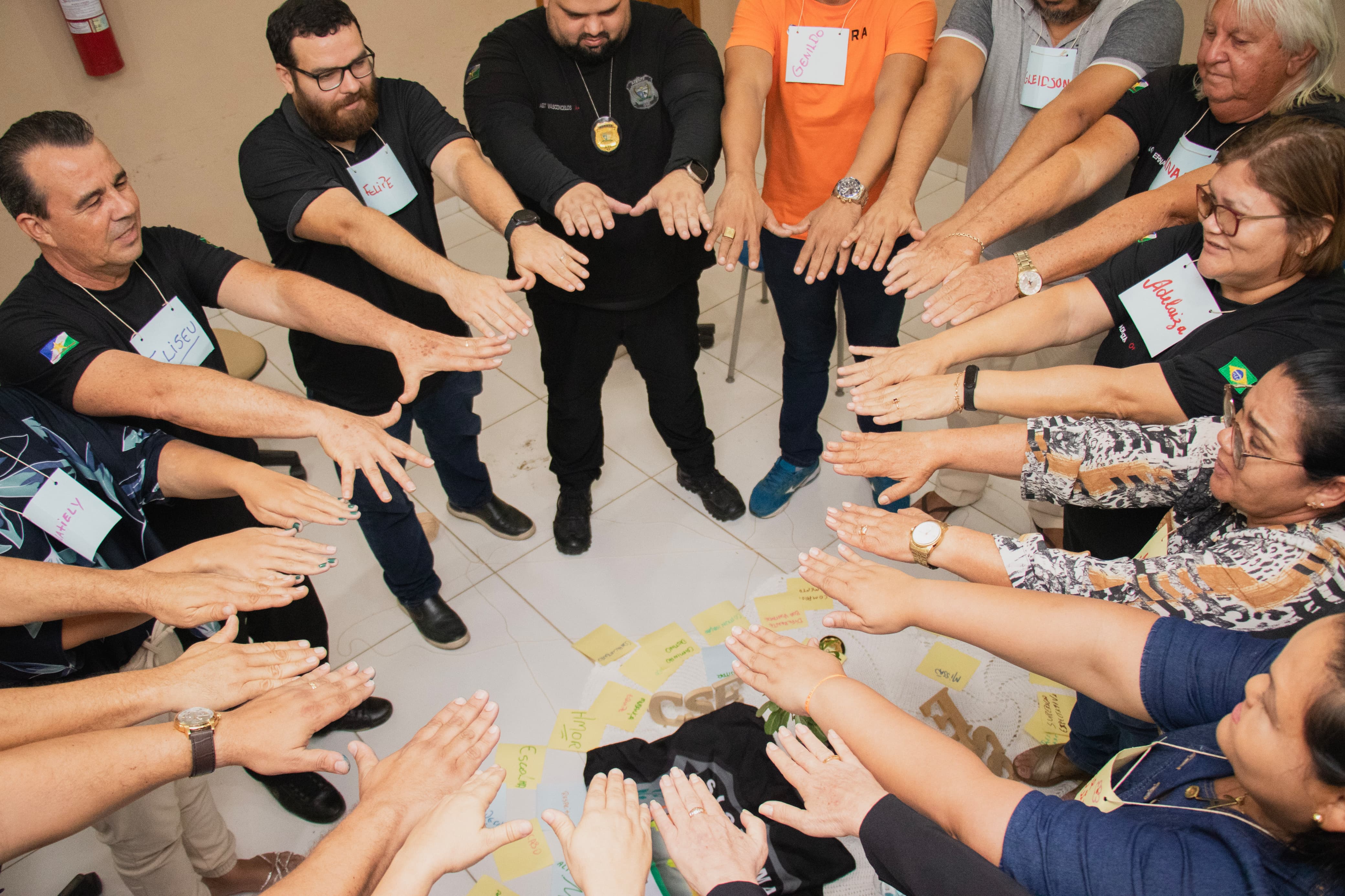 foto colorida de um grupo de pessoa em círculos com mãos para frente