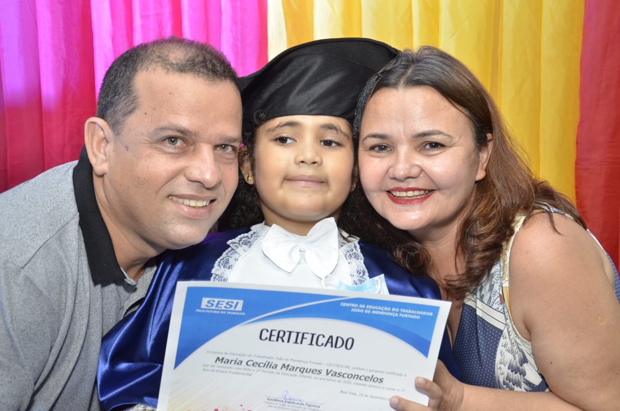 Foto de uma família, pai, mãe e uma criança segurando um certificado.