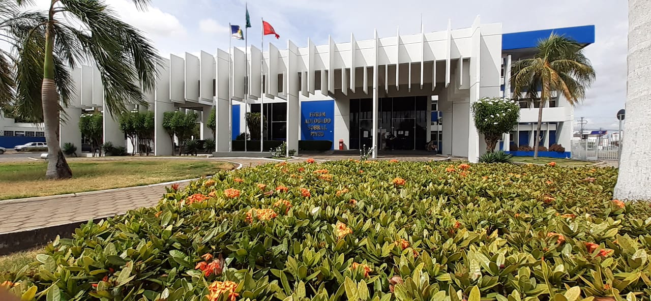 Foto frontal da área externa do Fórum Sobral Pinto, com as plantas da frente em primeiro plano.  