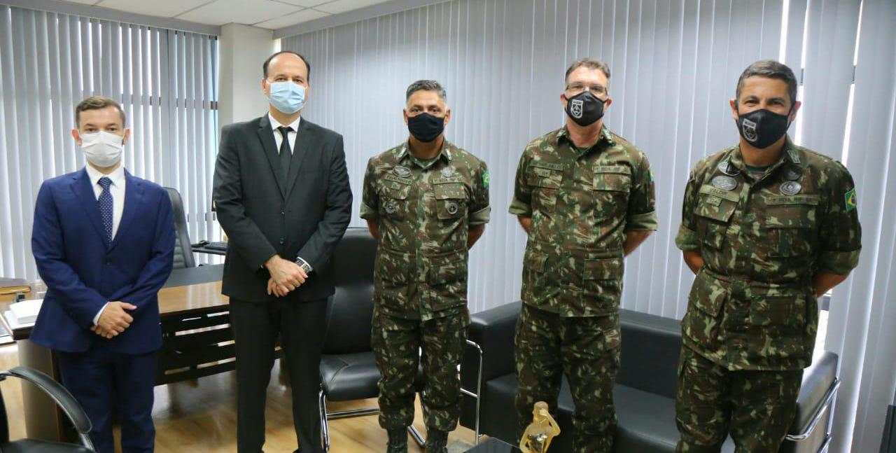 Foto com o Presidente do Tribunal de Justiça de Roraima, desembargador Cristóvão Suter;  o juiz auxiliar da Presidência do TJRR, Bruno Costa, os dois vestidos com terno e gravata; O comandante da 1ª Brigada de Infantaria de Selva, General Adriano Fructuoso da Costa; o Assessor Jurídico, Tenente Coronel César Melo, e o Adjunto de Comando, Sub-Tenente Valdir Alves da Silva, vestidos com fardas do exército; todos de pé para foto oficial.