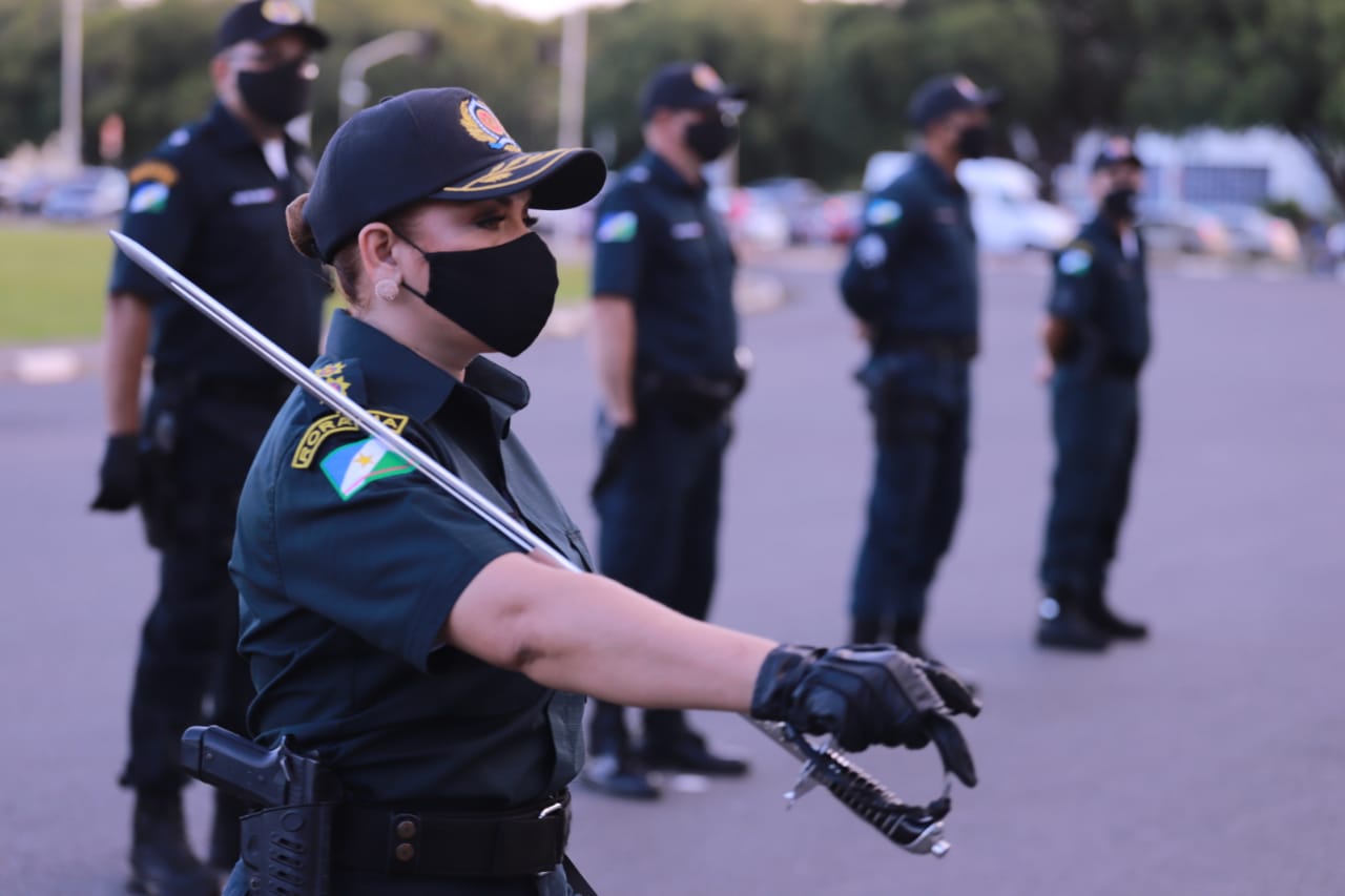 Foto da tenente coronel da Polícia Militar de Roraima Valdeane Alves de Oliveira segurando uma espada, e quatro policiais de pé atrás dela.