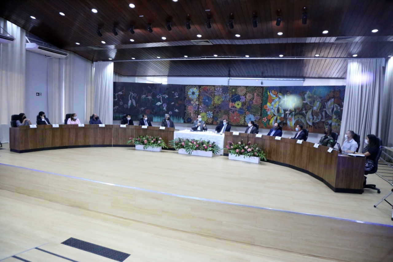 Foto do auditório do fórum Sobral Pinto, com duas bancadas grandes e uma mesa no centro com os conselheiros sentados atrás delas, participando de reunião.