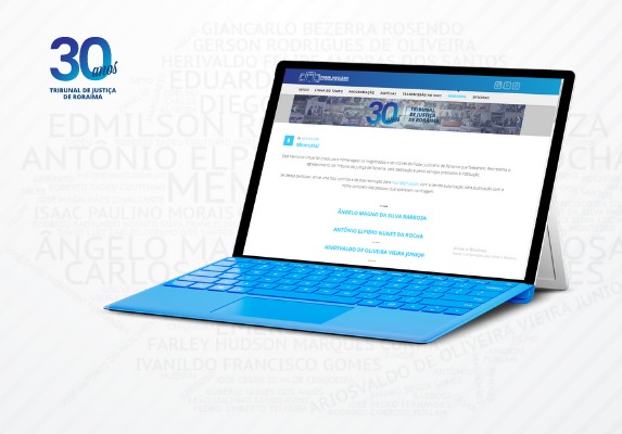 Imagem de um notebook, na sua tela está a página do Tribunal de Justiça no memorial virtual, ao fundo da imagem aparecem alguns nomes de servidores falecidos.