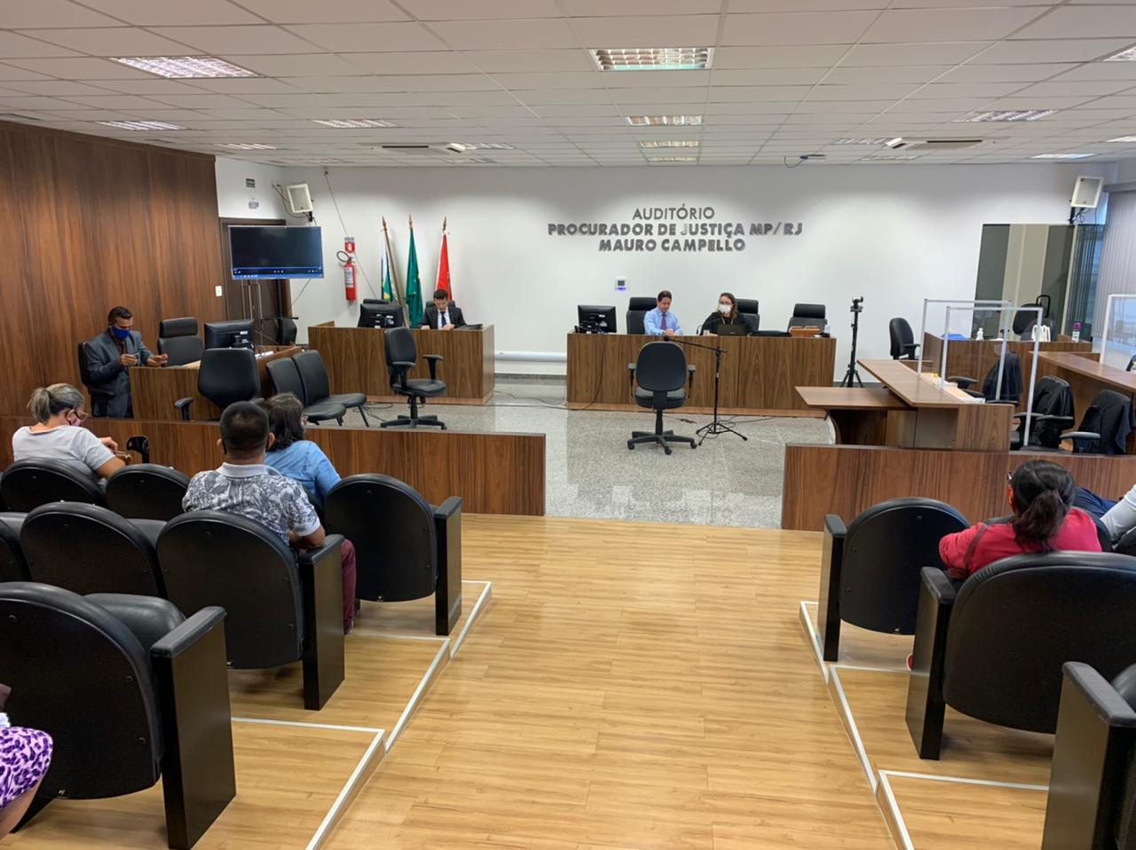 Foto do Tribunal do Júri no auditório, com pessoas sentadas assistindo o julgamento.