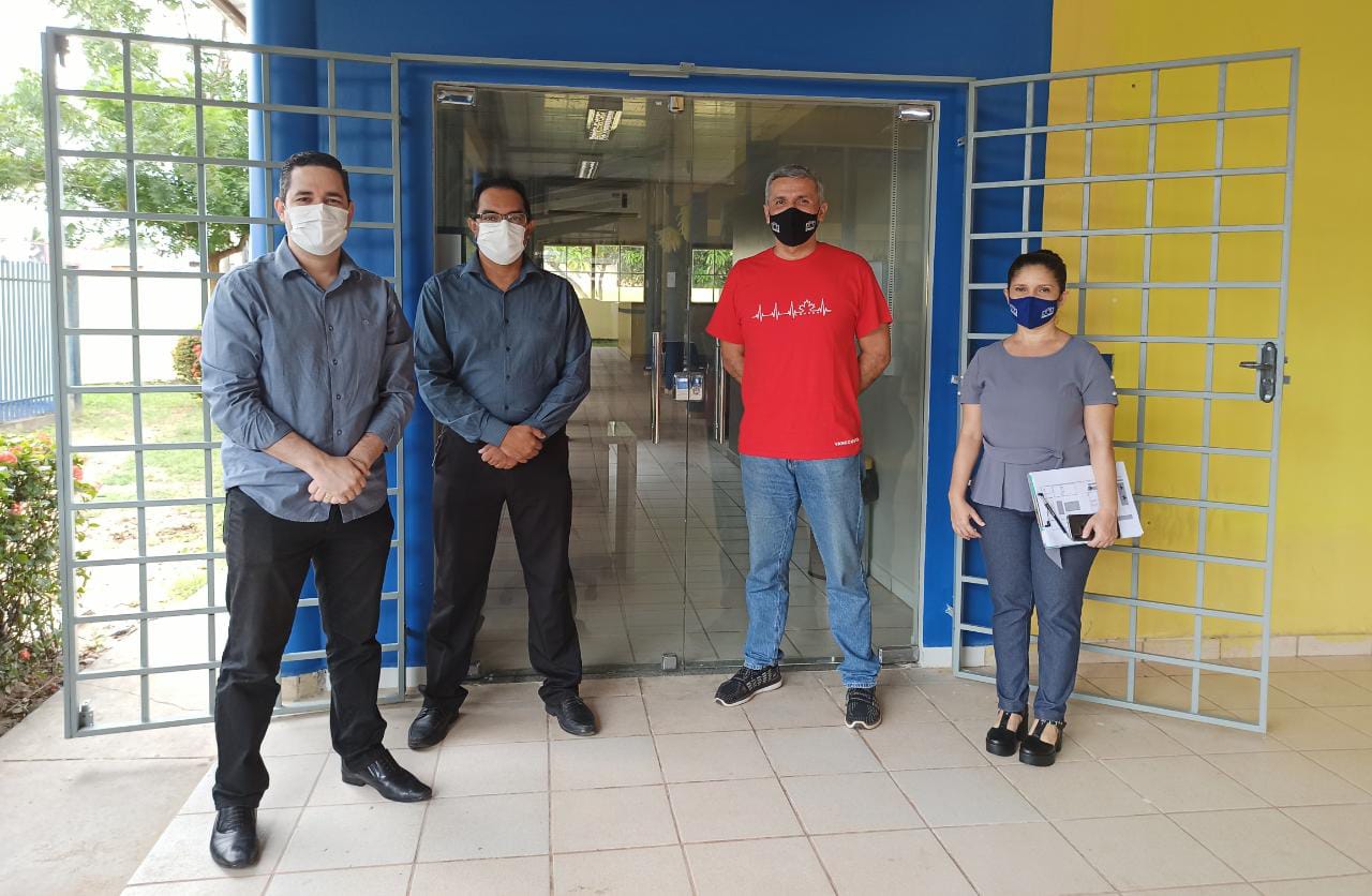 Quatro servidores do Tribunal de Justiça de pé posando para foto, em frente a porta de grade.