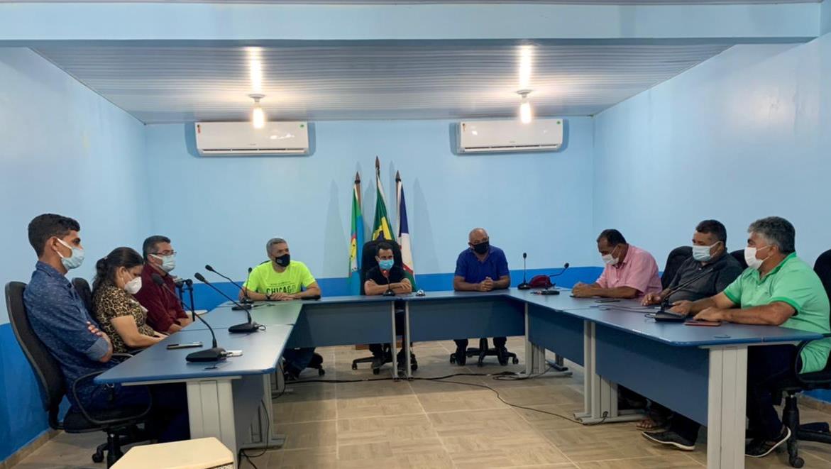 Equipe do tribunal de Justiça em reunião na Câmara Municipal de Caroebe, sentados em cadeiras atrás de mesas reunidas em formato de “U”.