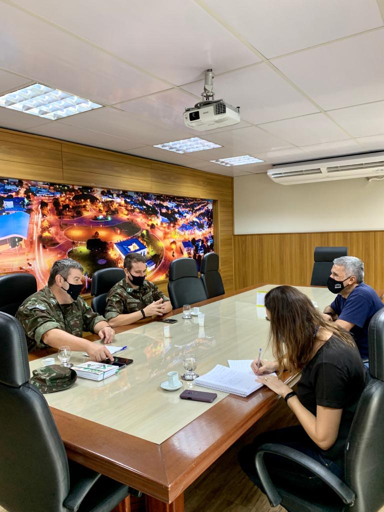 Servidores do Tribunal de Justiça sentados em mesa de reunião com representantes do exército.