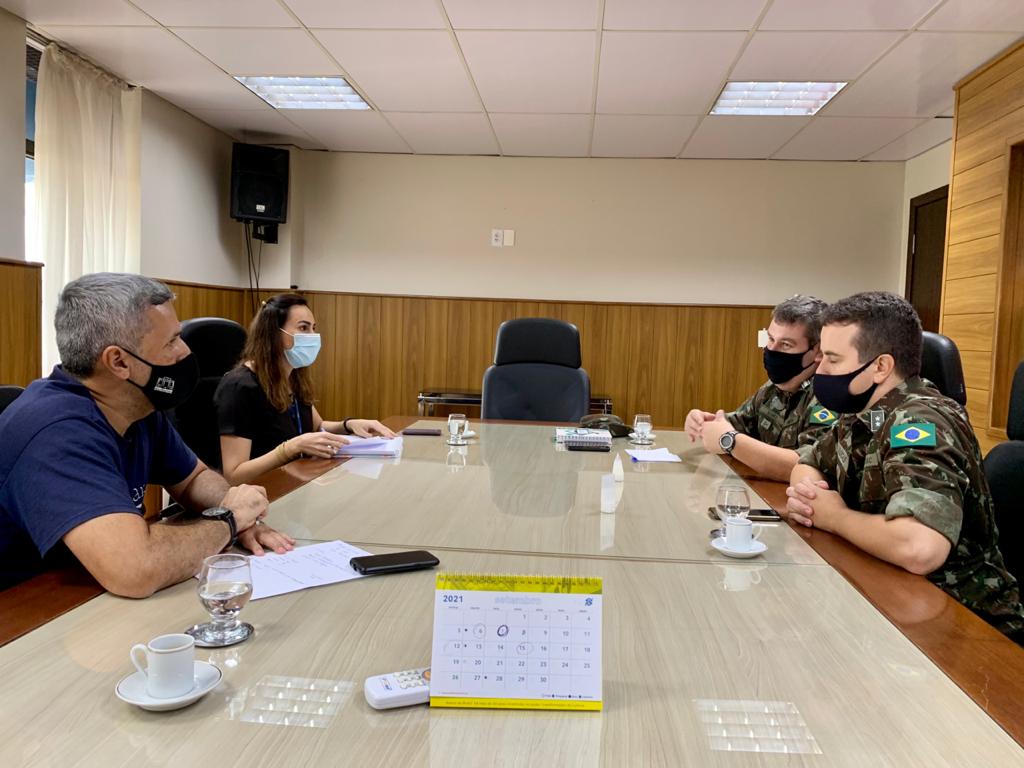 Servidores do Tribunal de Justiça sentados em mesa de reunião com representantes do exército.