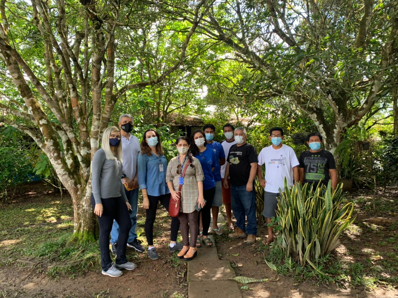 Servidores de pé posando para foto com árvores ao fundo na Comunidade Waimiri-Atroari.