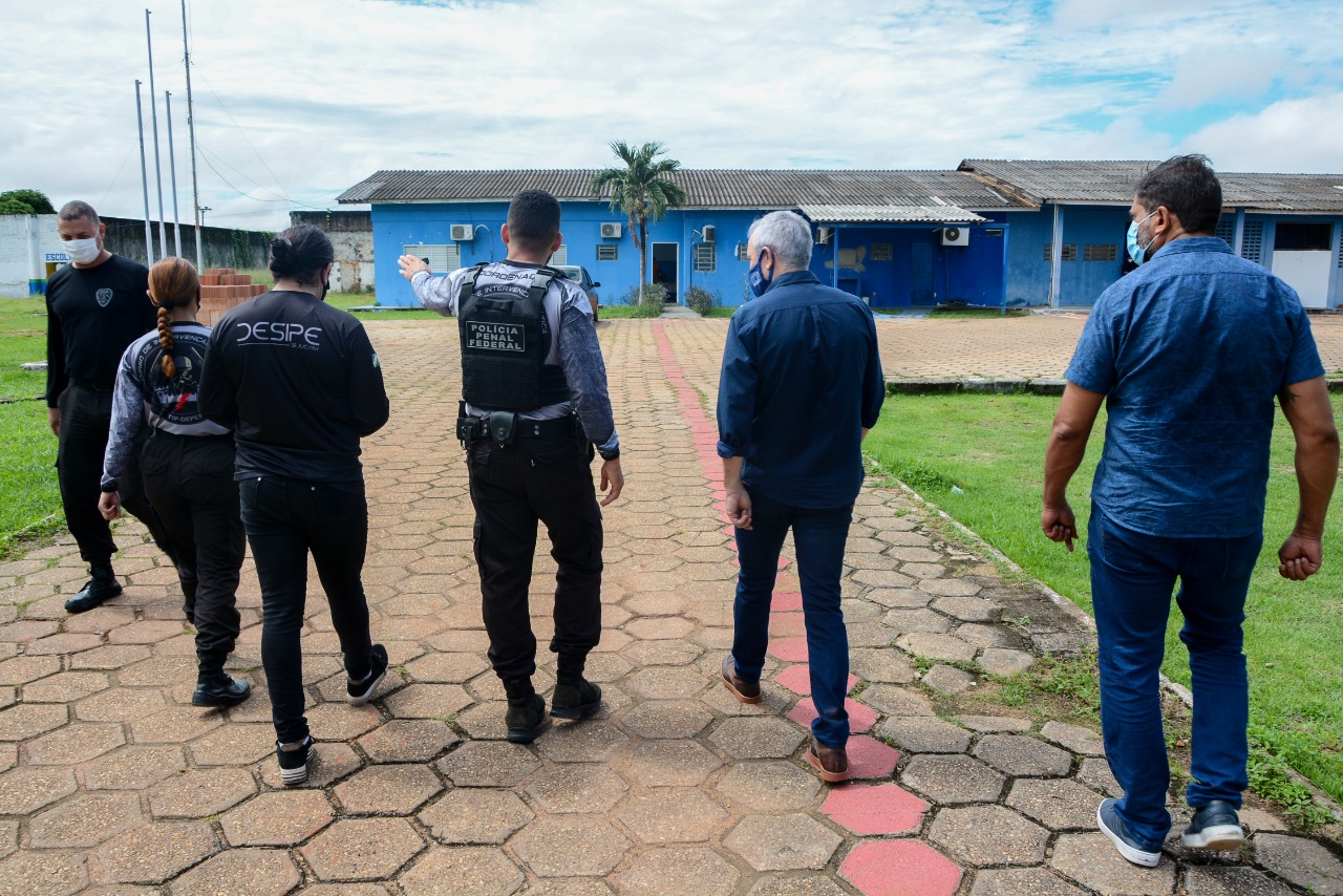 Pessoas de costas andando em direção à unidade prisional.