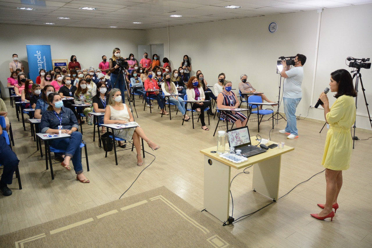 Mulheres sentadas em filas asssistindo a palestrante falar sobre o cancer de mama 