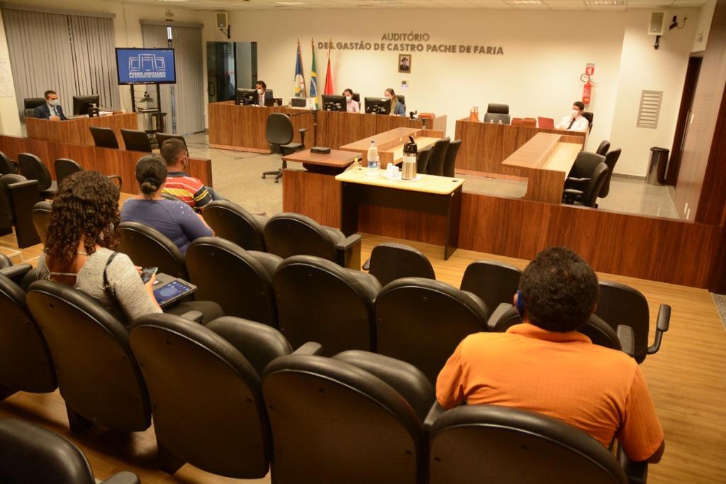 Imagem colorida contém pessoas sentadas no Auditório Des. Gastão de Castro Pache de Faria, durante audiência. 