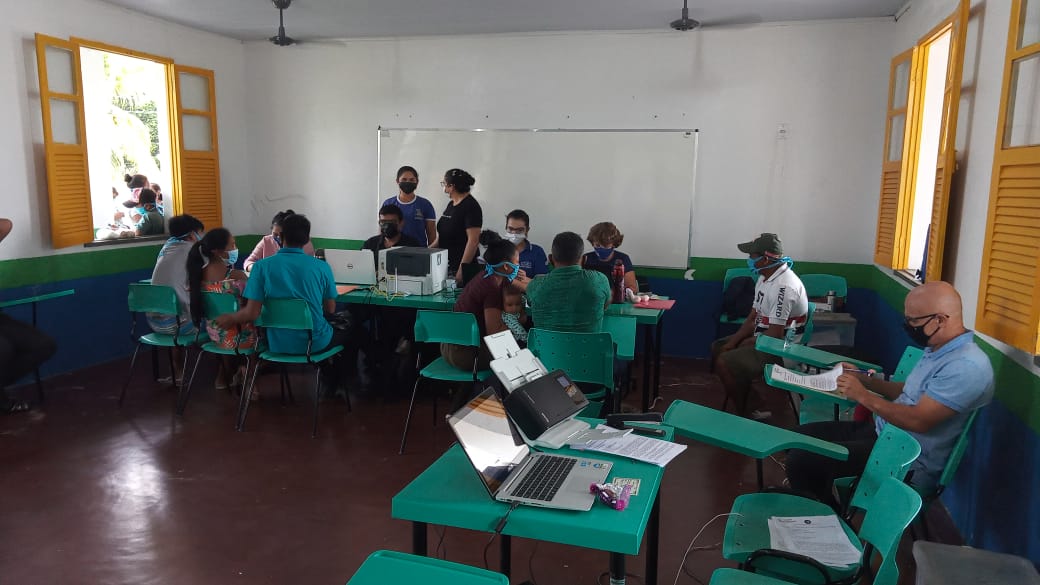 Foto colorida mostra pessoas sendo atendidas pela Justiça Itinerante em uma sala de aula. 