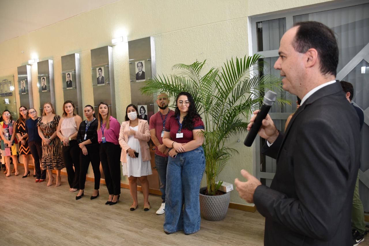 Imagem colorida mostra o presidente do TJRR, desembargador Cristôvão Súter, falando ao microfone durante  café da manhã especial em alusão ao dia das Mães, com servidoras e estagiárias do Poder judiciário de Roraima no fundo da imagem. 