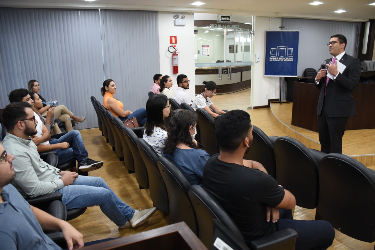 A imagem colorida mostra o juiz auxiliar de Gabinete do Superior Tribunal Militar (STM), Flávio Albuquerque, palestrando durante a Residência Judicial. No púlpito encontram-se residentes do programa assistindo à palestra. 