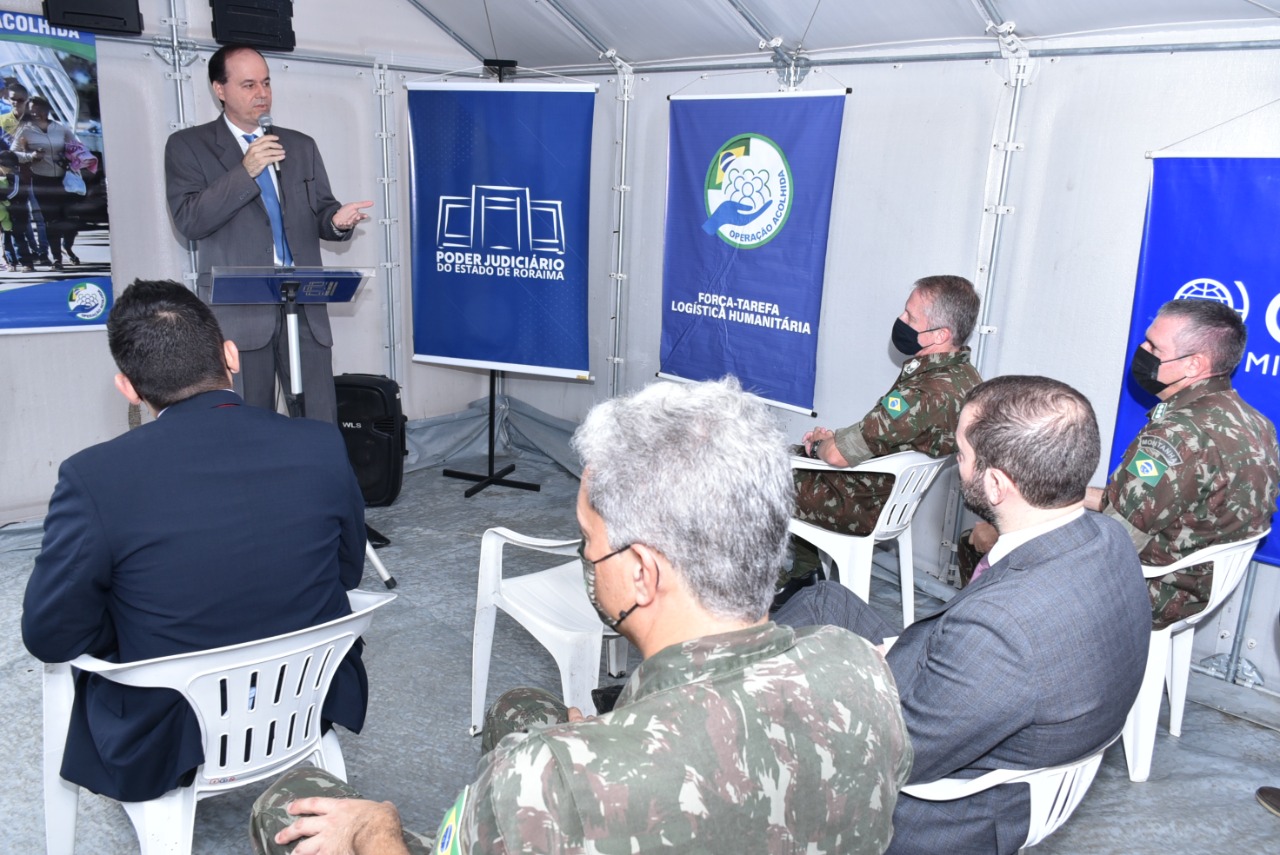 Imagem colorida contém o presidente do TJRR, desembargador Cristôvão Súter falando no microfone durante inauguração do polo de atendimento do Justiça Cidadã no posto de triagem da Operação Acolhida.  