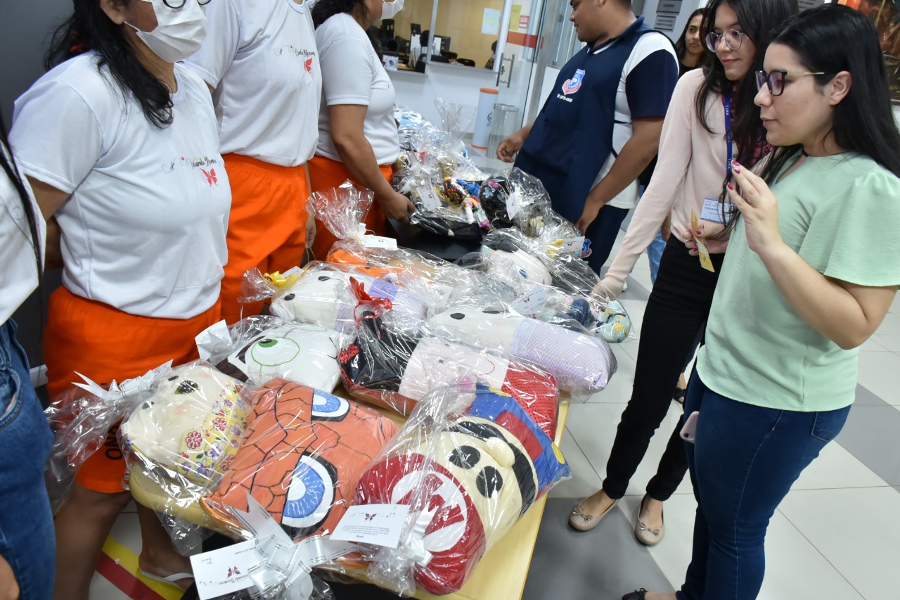  Imagem colorida contém reeducandas da Cadeia Pública Feminina expondo seus artesanatos, durante a quarta exposição do projeto Costurando Recomeços, que ocorreu no Fórum Criminal do TJRR. 