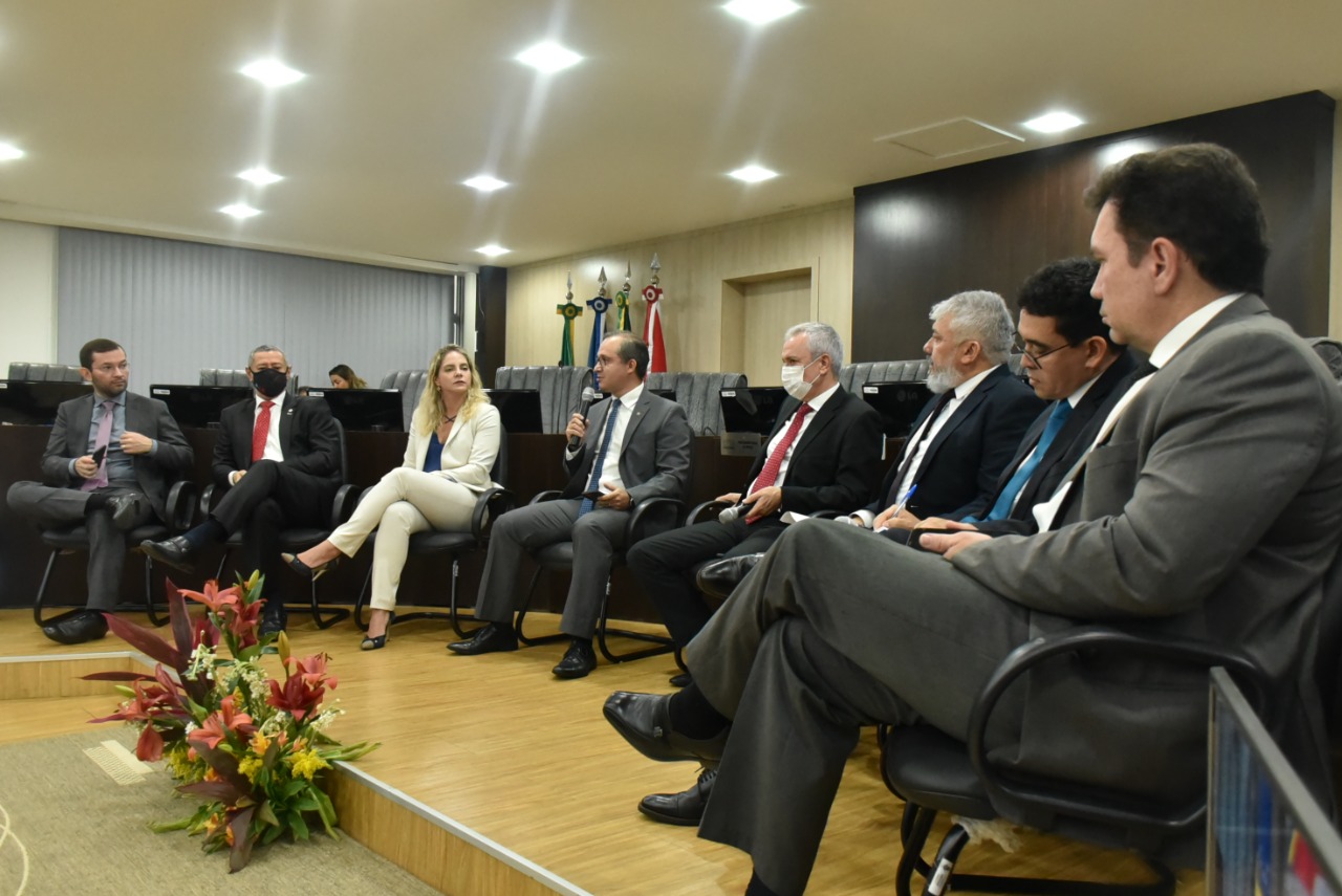 foto colorida mostra oito autoridades sentadas em poltronas pretas em formato de meia lua no Tribunal Pleno. Aparecem da esquerda para a direita: o juiz auxiliar da presidência do TJRR, Bruno Costa o presidente da OAB-RR, Ednaldo Vidal, a procuradora geral do município de Boa Vista, Marcela Medeiros, o promotor de Justiça, Márcio Rosa, o desembargador do TJRR,Almiro Padilha, o defensor público, Oleno Matos, o corregedor geral de justiça, juiz Breno Coutinho e o procurador geral do Estado, Jean Pierre Michetti. 