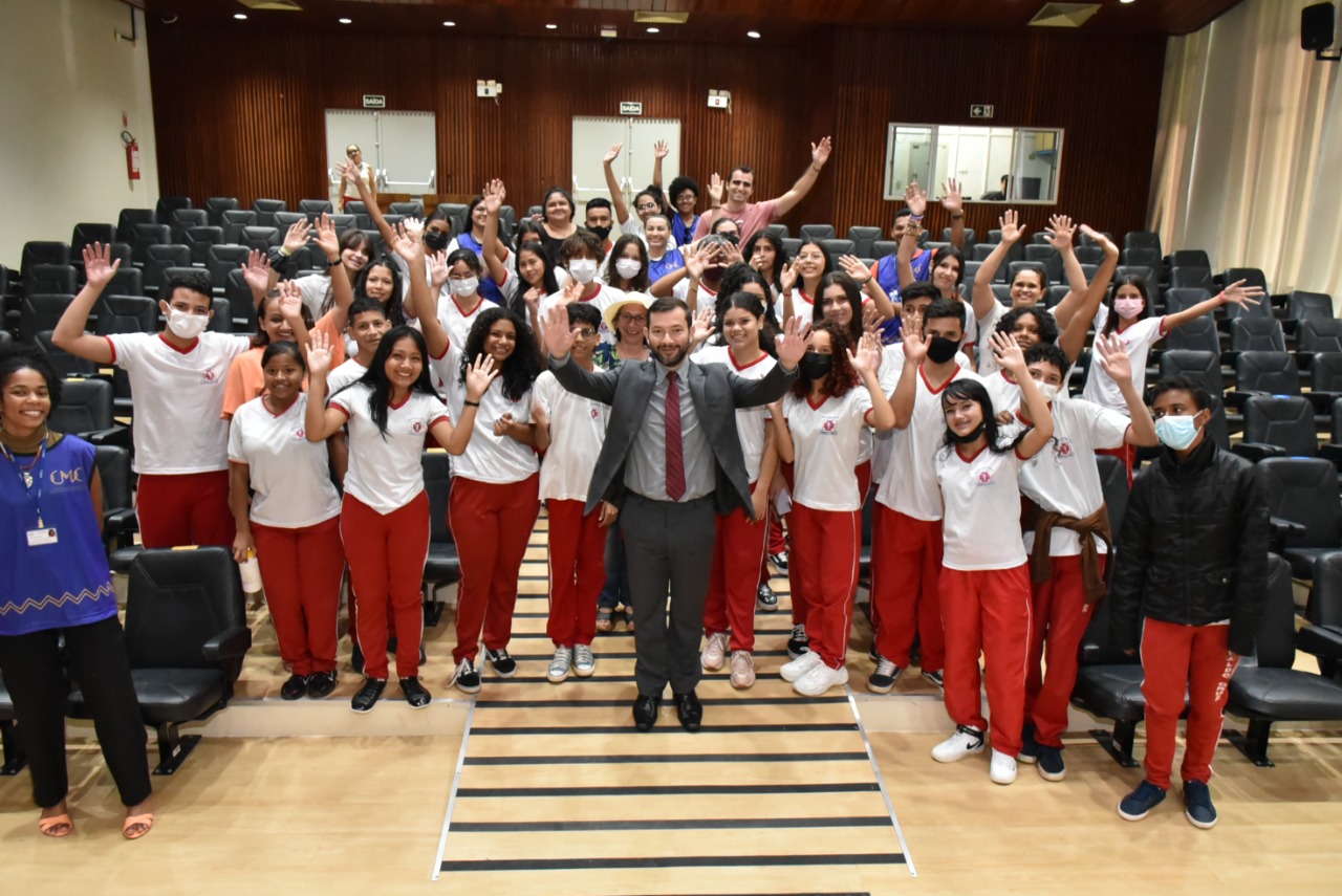 Imagem colorida dos alunos da Escola Estadual Oswaldo Cruz, juntamente com o  Juiz auxiliar do TJRR, Dr Bruno Fernandes Alves Costa, e servidores do TJRR,  posando posando para fotografia, no Tribunal do Pleno do TJRR. 