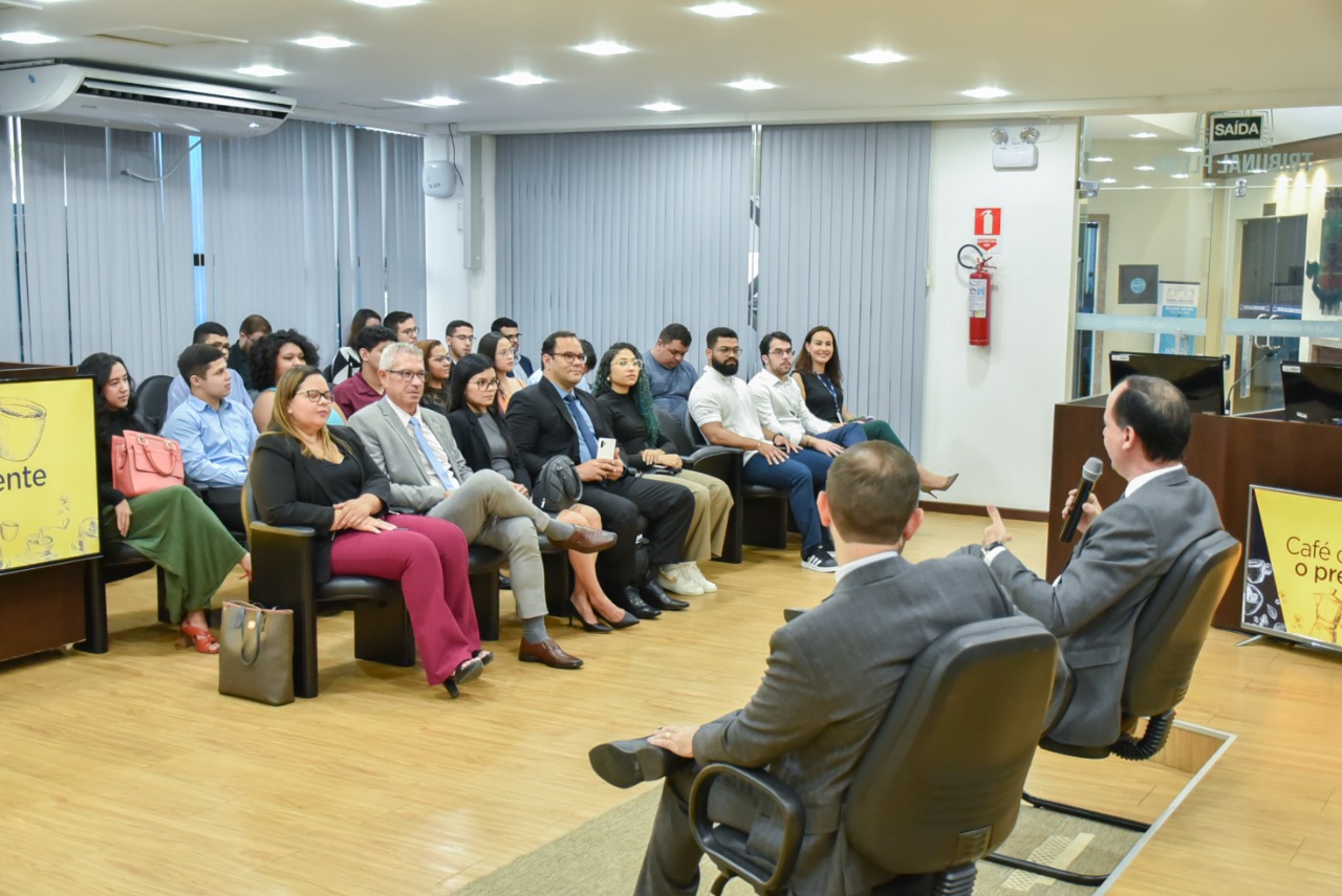 Imagem colorida contém o presidente do Tribunal de Justiça de Roraima (TJRR), desembargador Cristóvão Súter, sentado ao lado do Juíz auxiliar do TJRR, Dr. Bruno Fernandes Alves Costa, de frente para os acadêmicos de direito da Faculdade Cathedral, durante a quarta edição do programa Café com o presidente, do TJRR. 