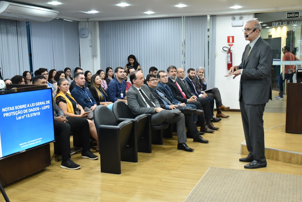 Imagem colorida em formato retangular mostra Sala de Sessões do Tribunal Pleno com alunos e alunas  do programa Residência Judicial, magistrados, magistradas  servidores, servidoras,  colaboradores e colaboradoras do Tribunal de Justiça de Roraima (TJRR) . Na primeira fileira está o desembargador Cristóvão Suter juntamente com vice-presidente, desembargador Erick Linhares, Juiz auxiliar da presidência Bruno Costa e demais magistrados  à frente palestrando, está o ministro do Superior Tribunal Militar (STM), José Barroso Filho.