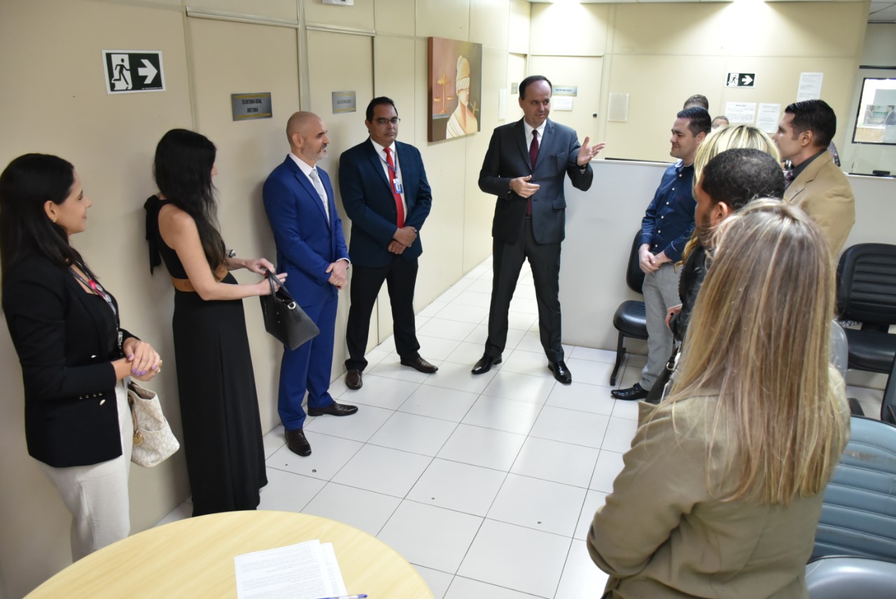 imagem colorida em formato retangular mostra o presidente do TJRR, desembargador Cristóvão Suter discursando para um grupo de homens e mulheres em um sala de cor marfim com assentos cinzas.