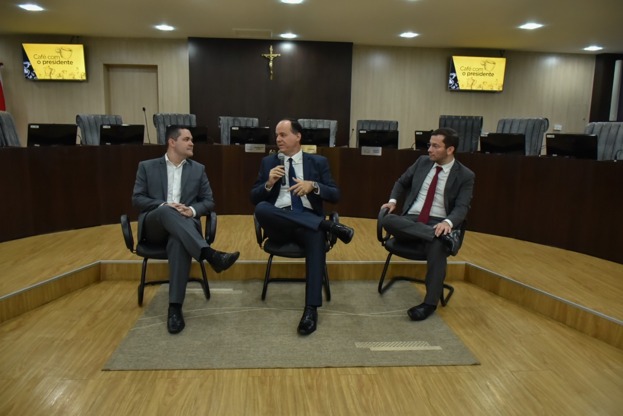 Imagem colorida em formato retangular, mostra o presidente do TJRR, desembargador Cristóvão Suter, o juiz auxiliar da presidência, Bruno Costa e o secretário-geral, Felipe Queiroz, durante a uma roda de conversa com os  acadêmicos de direito da Faculdade Cathedral.