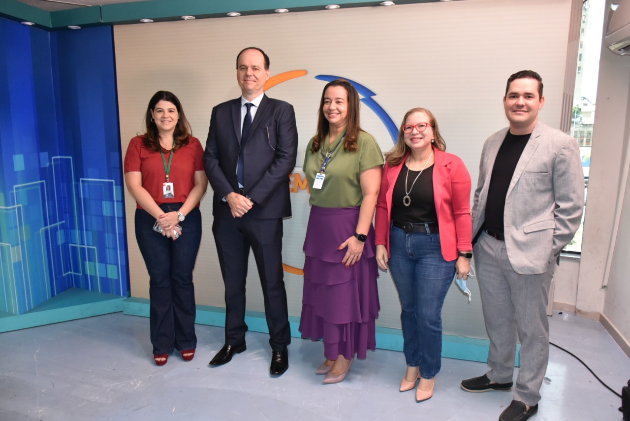 Imagem colorida em formato retangular mostra o presidente do Tribunal de Justiça de Roraima, desembargador Cristóvão Suter, o secretário-geral, Felipe Queiroz, a coordenadora do NUCRI, Débora Morais a superintendente de Comunicação da TV Assembléia, Sônia Lúcia Nunes Pinto e a jornalista Camilla Dall´Agnol, posando em pé para foto.