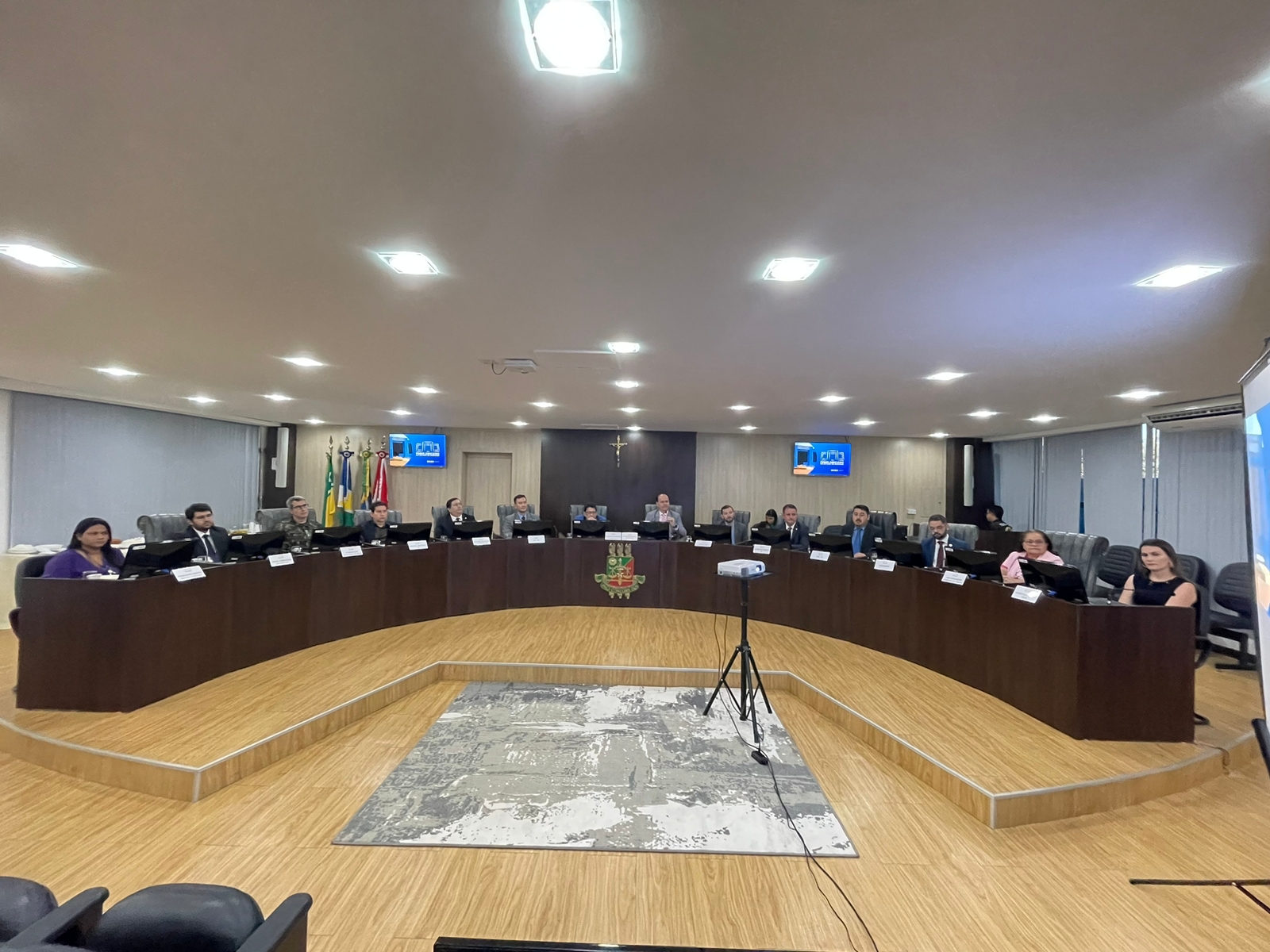 Imagem 1- Imagem colorida em formato retangular mostra a bancada do Sala de Sessões do Pleno no Palácio da Justiça ocupada pelo Conselho Consultivo Interinstitucional, composto por onze homens e três mulheres.