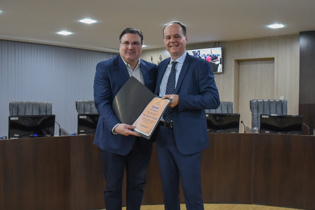 Imagem colorida em formato retangular mostra o presidente do TJRR, desembargador Cristóvão Suter ao lado do diretor da Rede Amazônica em Roraima, Joel Gomes, o mesmo segura o diploma de “Mérito Judiciário” em suas mãos.