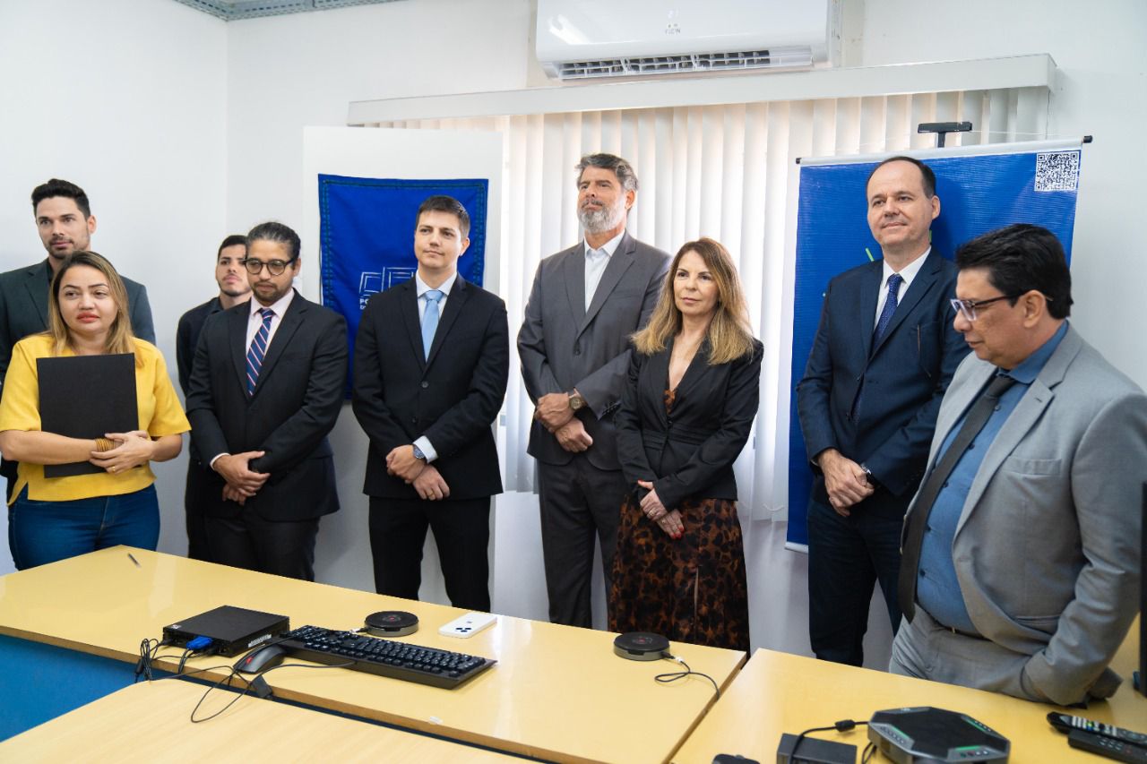 Imagem colorida em formato retangular mostra o presidente do Tribunal de Justiça de Roraima, desembargador Cristóvão Suter, o vice-presidente do Poder Judiciário de Roraima, Jésus Nascimento, juíza titular da Comarca de Bonfim, Liliane Cardoso, o Juiz Luiz Fernando Mallet e cinco servidores do Poder Judiciário em pé, atrás de uma mesa na cor marfim.