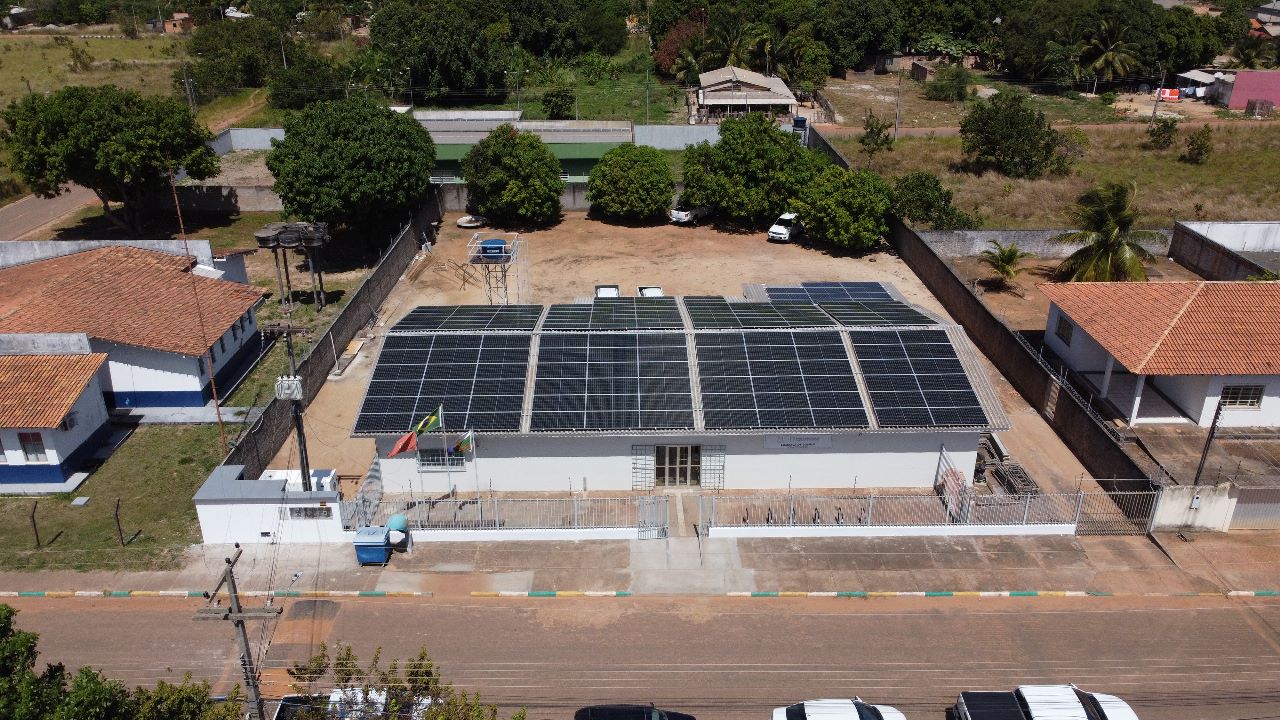 Imagem colorida aérea  em formato retangular mostra o teto da comarca de Bonfim com as placas de energia solar instaladas. 