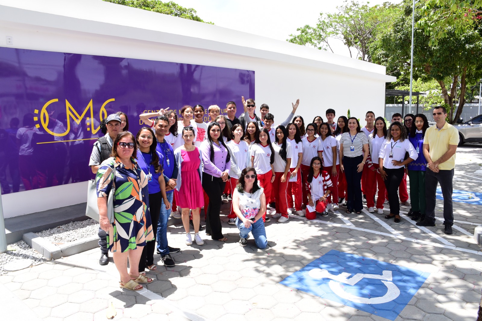 Imagem colorida mostra os alunos da Escola Estadual Oswaldo Cruz, além de professores, servidores do TJRR e colaboradores do Museu Integrado de Roraima, posando para a foto em frente a fachada do centro de memória e cultura do poder judiciário de Roraima.