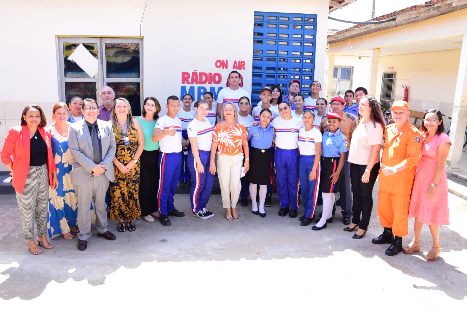 Imagem colorida mostra o presidente do Tribunal de Justiça de Roraima, desembargador Jésus Nascimento e a coordenadora do Programa Justiça Comunitária, Marcelle Wottrich posando para a foto ao lado de alunos, alunas, professores, professoras e colaboradores da  da Escola Estadual Militarizada Maria dos Prazeres Mota. 