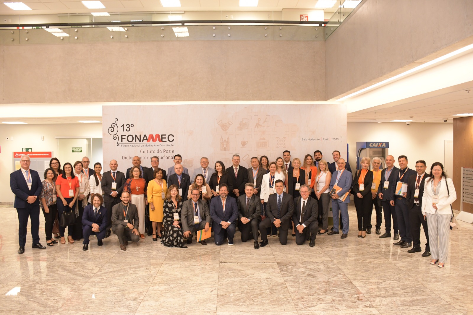 Imagem colorida mostra um grupo de 43 homens e mulheres posando para a foto. Atrás um banner com o logotipo do 13º Fonamec