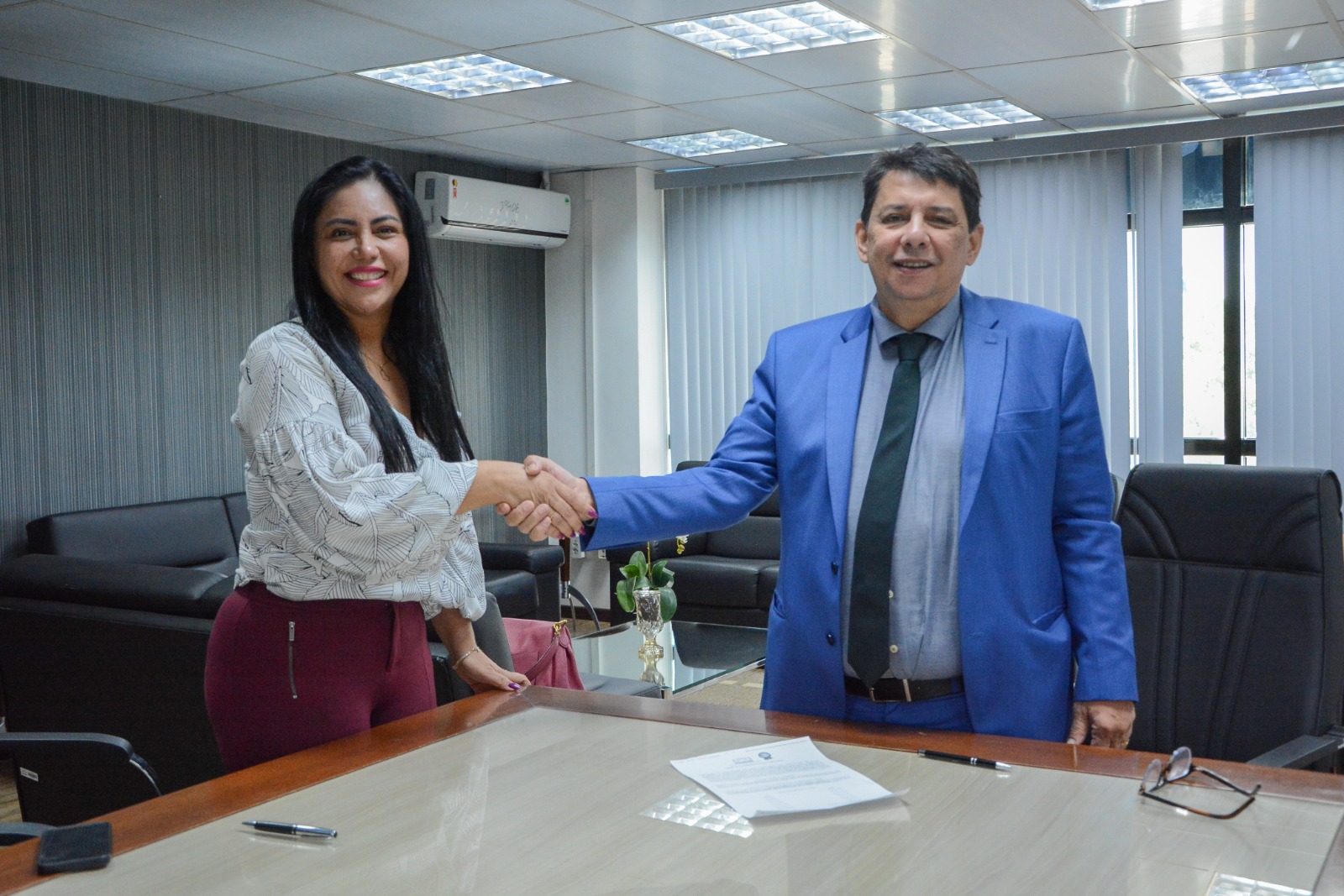 foto colorida do presidente do TJRR, desembargador Jésus Nascimento dando aperto de mão em uma servidora da prefeitura