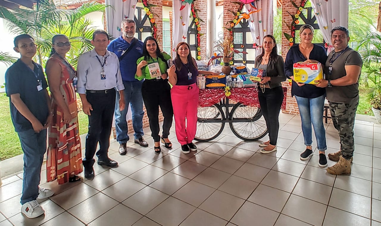 foto colorida de servidores da ouvidoria pousando para a foto durante a entrega de itens de higiene para idosos