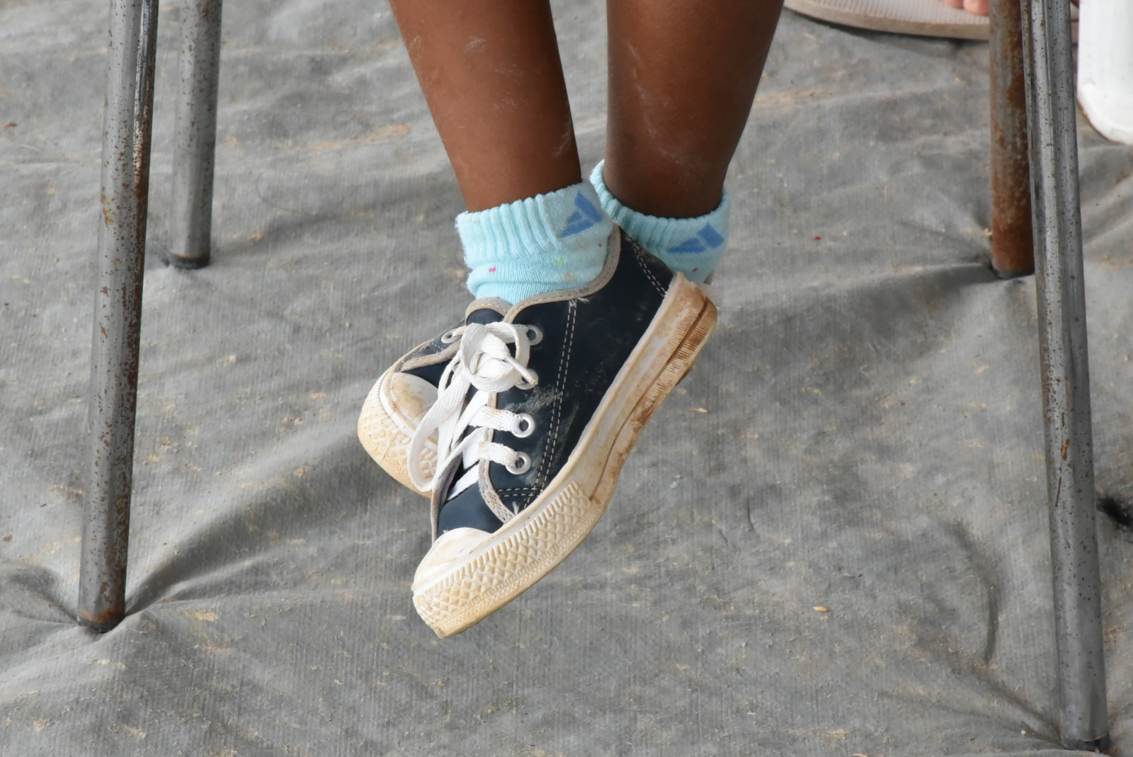 foto colorida dando enfoque no pé de uma criança com sapatos sujos