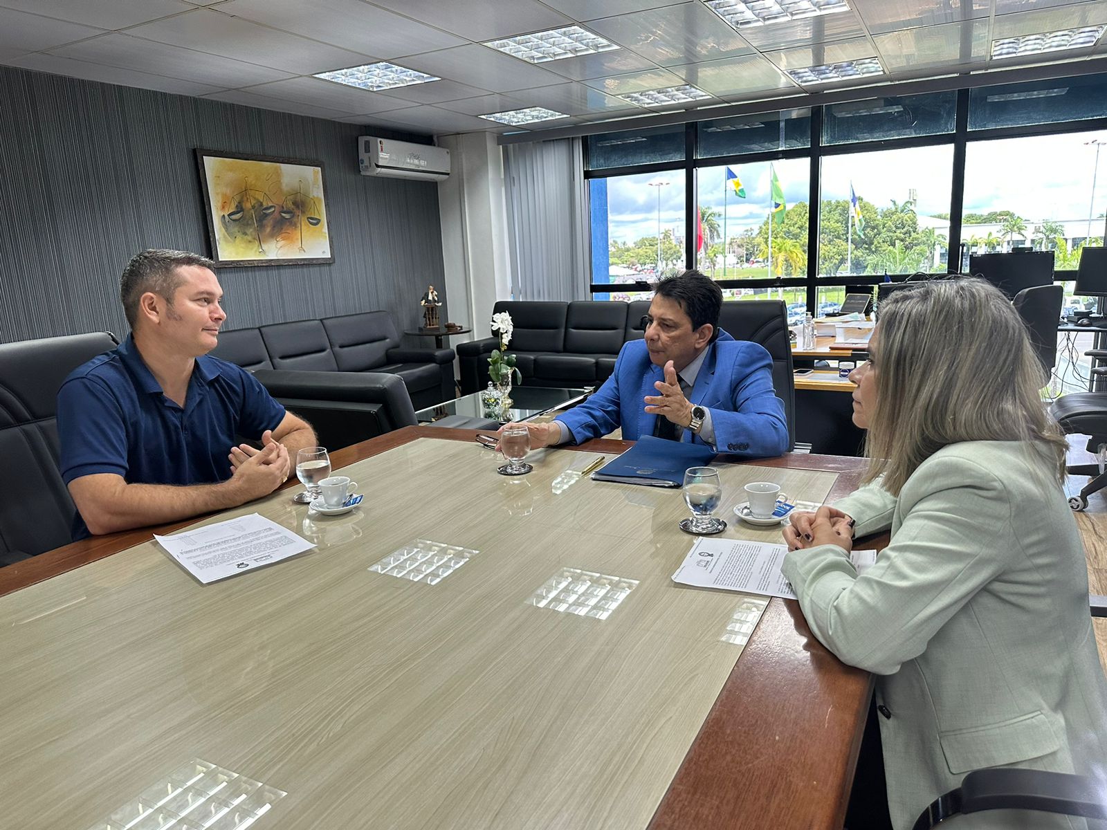 foto colorida mostra o presidente do Poder Judiciário de Roraima, desembargador Jésus Nascimento, a coordenadora do Núcleo de Precatórios do TJRR, Valdira Silva, e o prefeito de São Luiz, James Moreira Batista, sentados na mesa de reunião na sala da presidência do Tribunal de Justiça de Roraima.