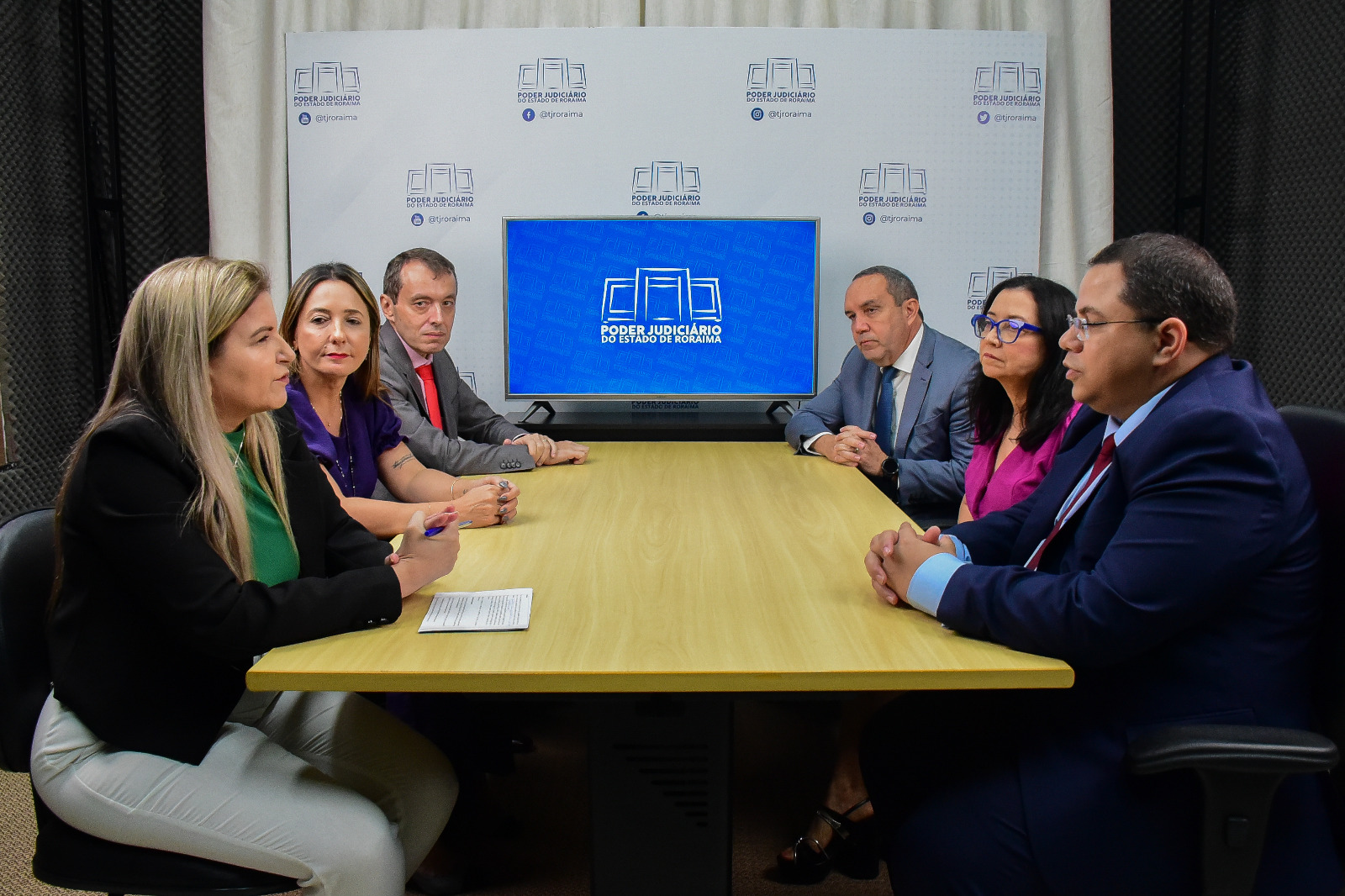 Foto colorida de uma mesa de reunião com o pessoal da comitiva com o NUCRI