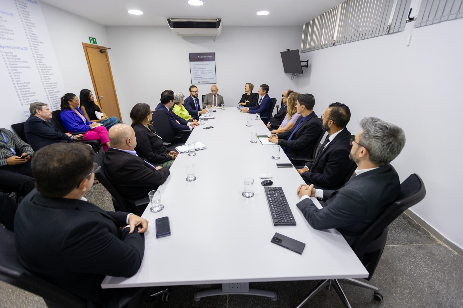 foto colorida de uma mesa de reunião com pessoas sentadas 
