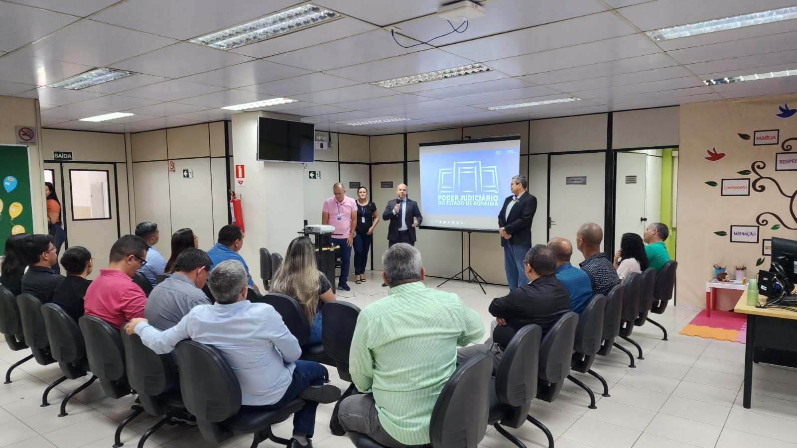 ffoto colorida da tuma sentada em direção ao slide e ao mediador da aula