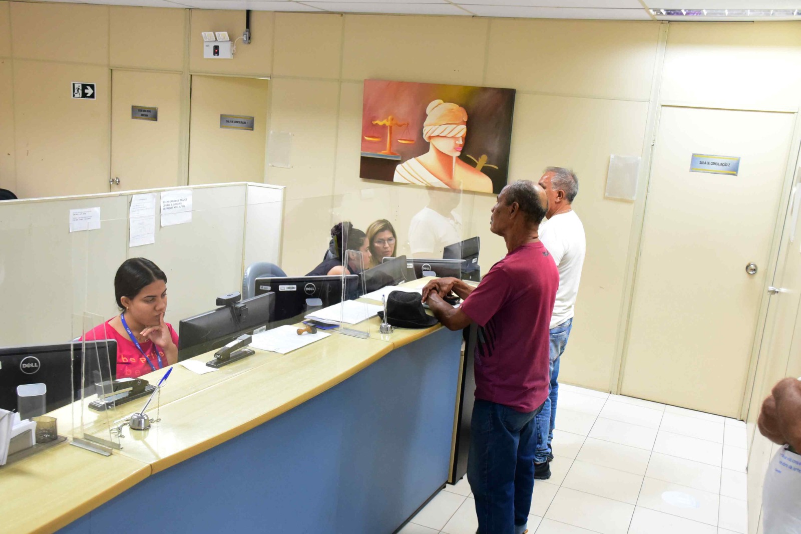 foto colorida mostrando o balcão de atendimento com dos homens sendo atendidos