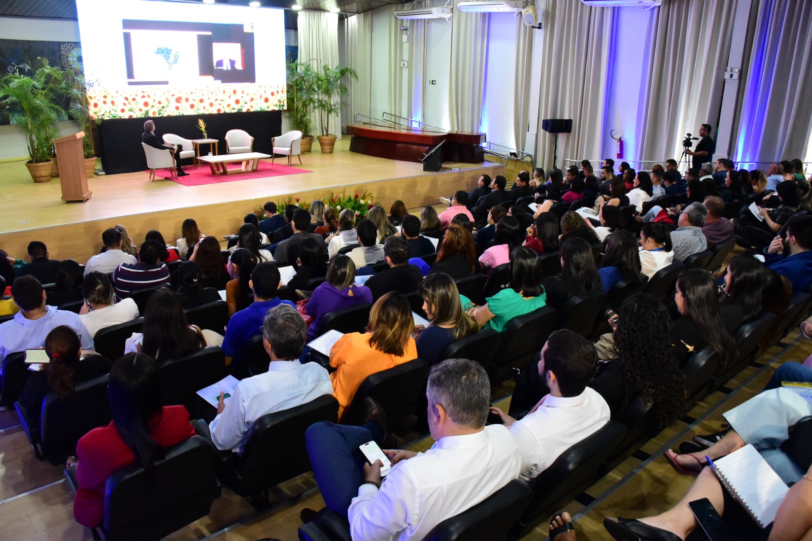 foto colorida do auditório cheio com pessoas sentadas