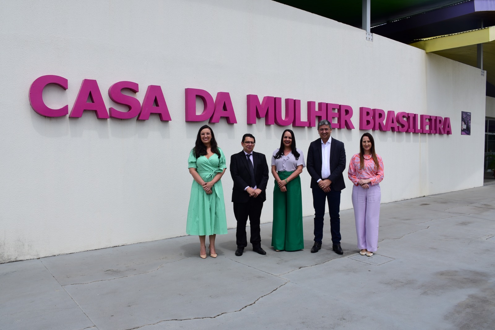  imagem colorida mostra cinco pessoas posando para fotografia, em frente a fachada escrita “Casa da Mulher Brasileira”. Na imagem, está o presidente do TJRR, desembargador Jésus Nascimento, ao lado do vice-governador, do Estado de Roraima, Edilson Damião Lima, a secretária da Setrabes, Tânia Soares, a juíza titular da Coordenadoria Estadual da Mulher em Situação de Violência Doméstica do TJRR, Suelen Márcia Alves e da promotora Lucimara Campaner.